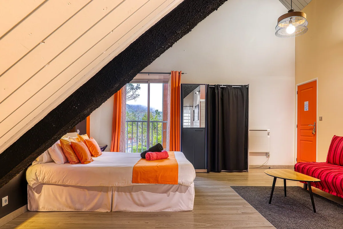 La chambre Fournaise sous son plafond en pente, linge orange
