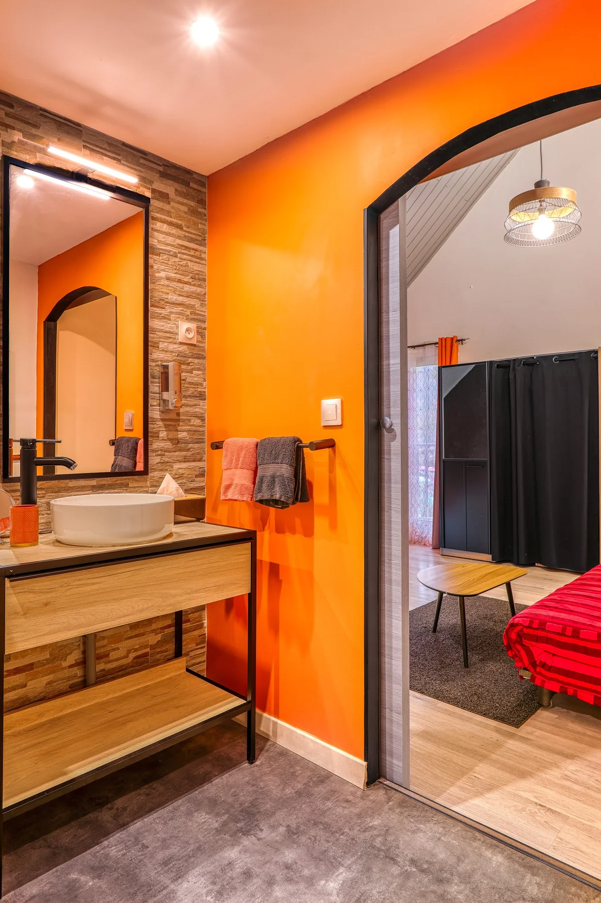 La salle de bain de la chambre Fournaise, mur orange et miroir en arche