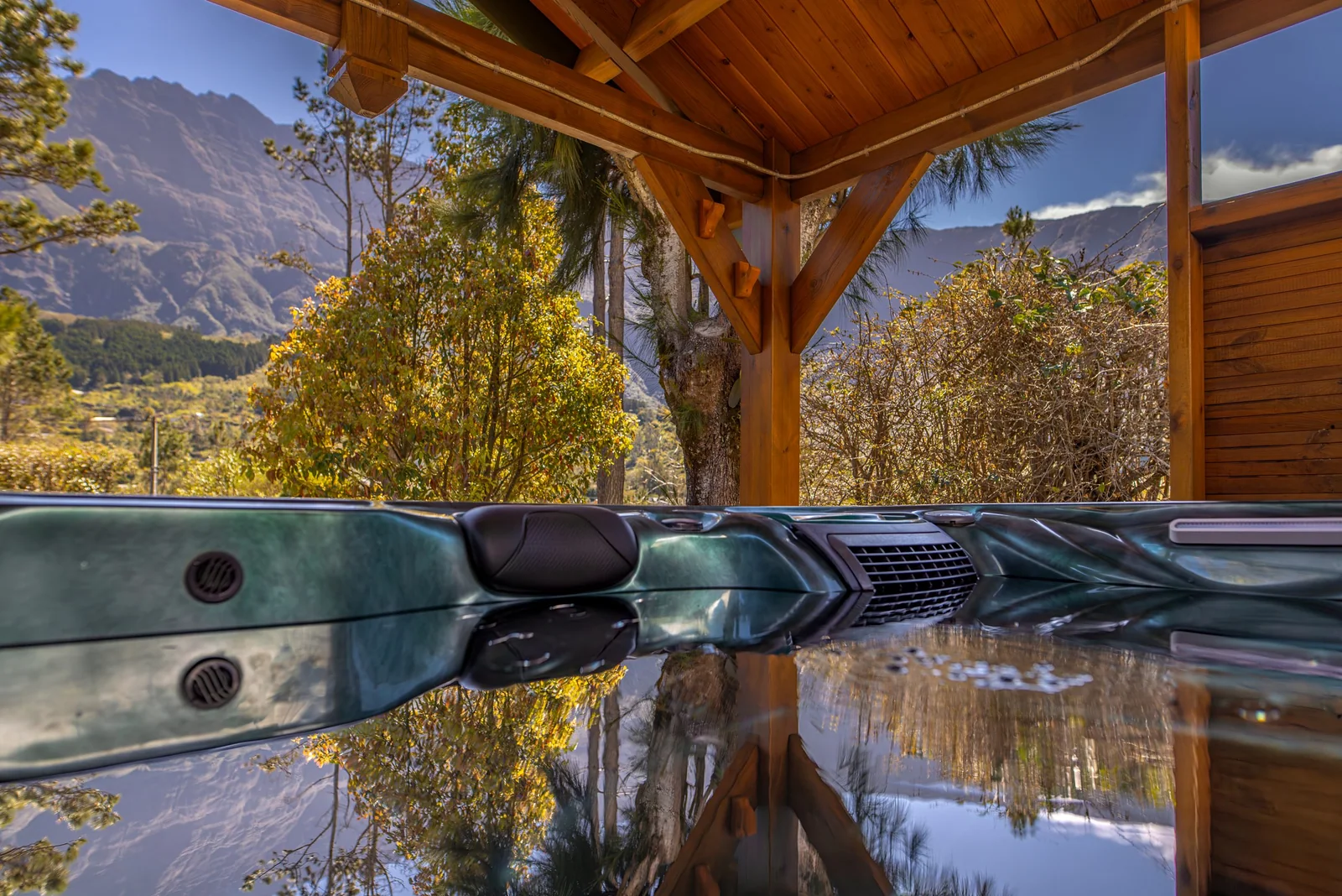 Le jacuzzi de la villa sous son abri en bois, avec les montagnes du cirque en face