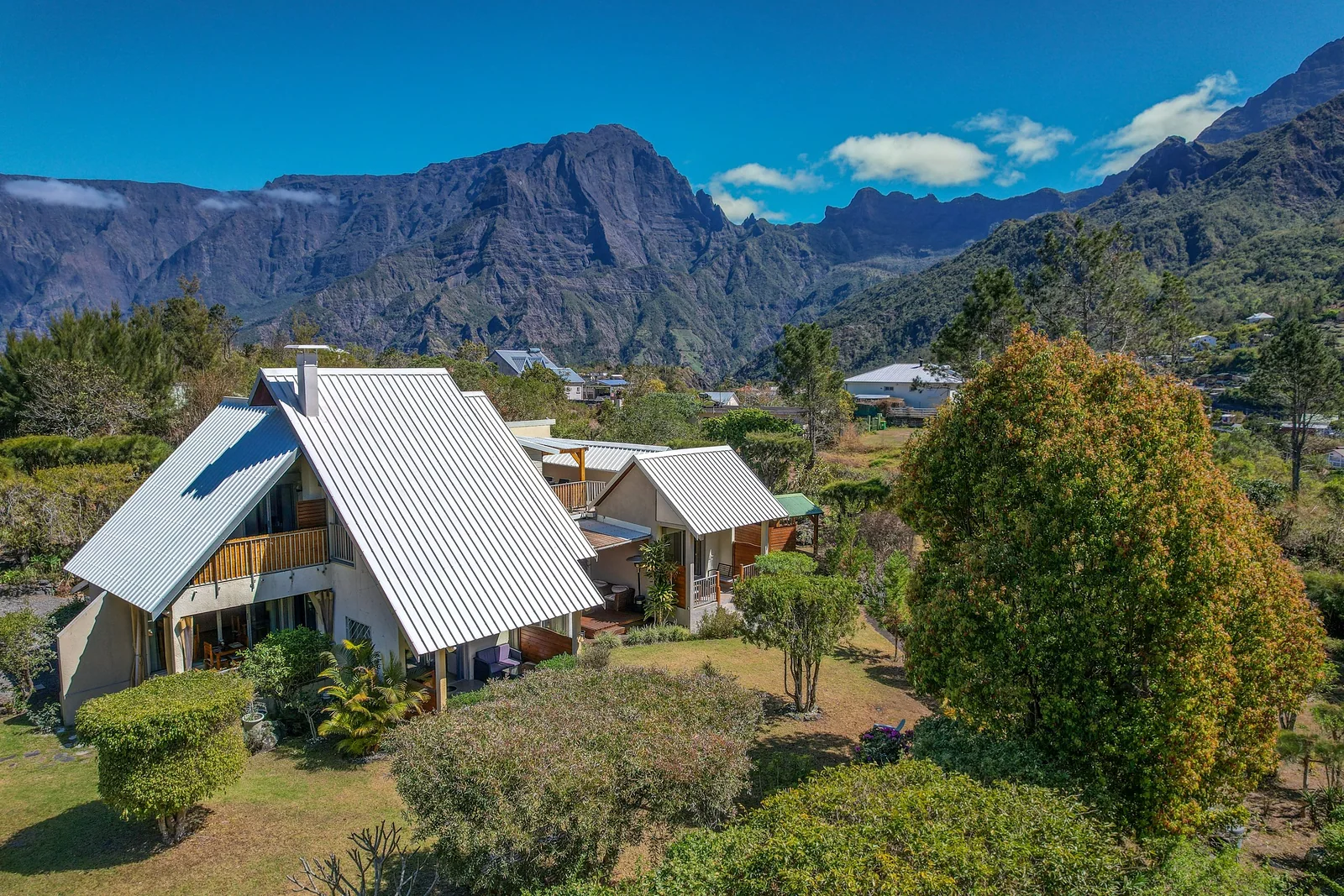 La Villa Soalic, maison blanche au toit de tôle dans son jardin, sous les remparts du cirque de Cilaos